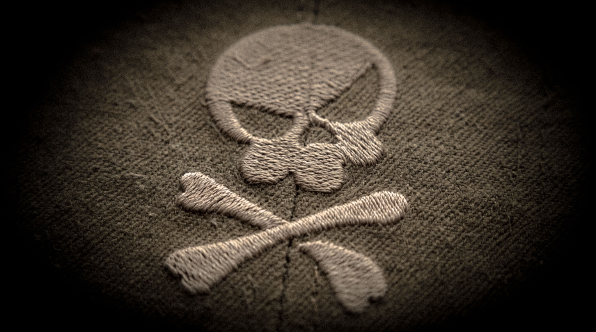 A close-up of the SKULLBY skull and crossbones embroidered on textured fabric