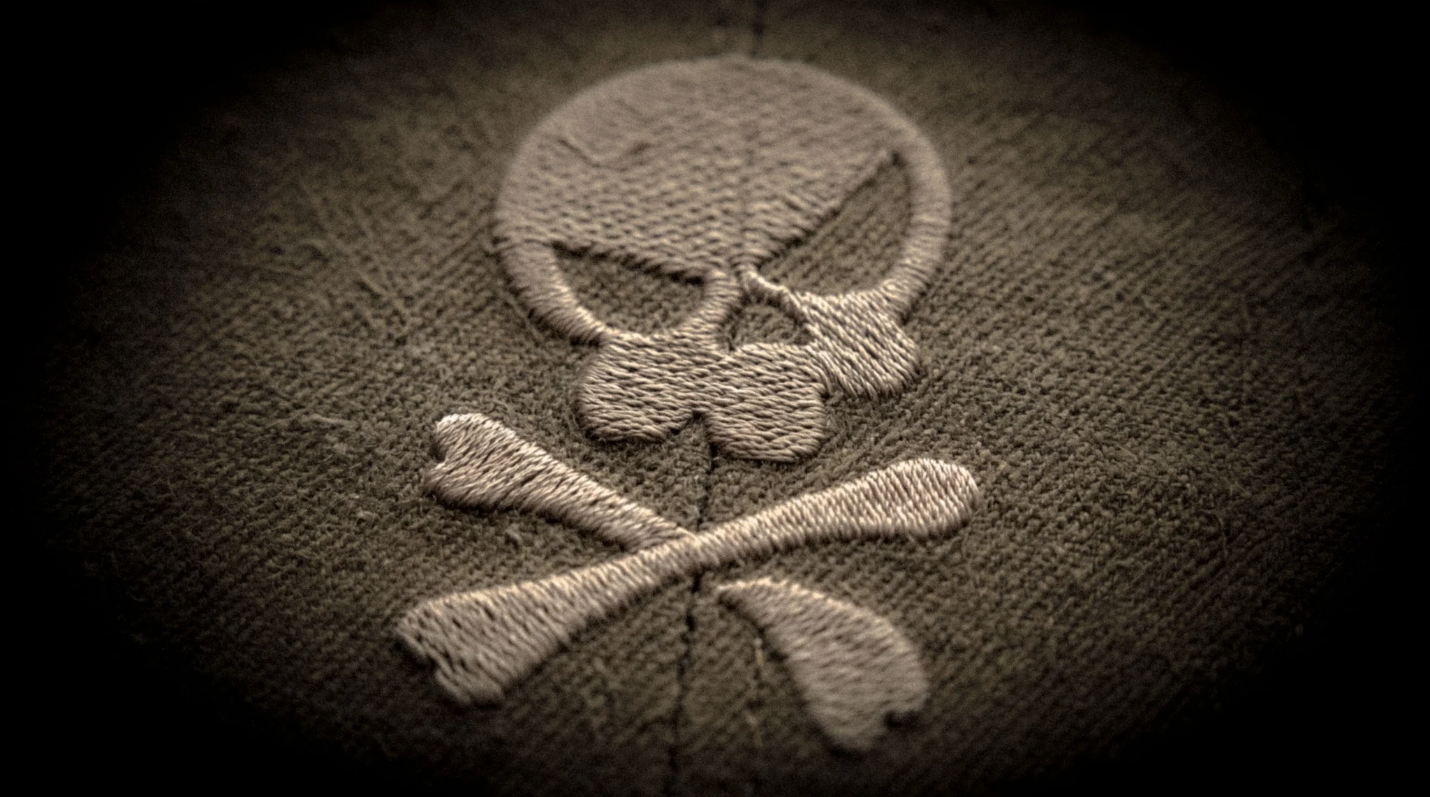 Embroidered skull and crossed bones in light thread on textured dark cloth